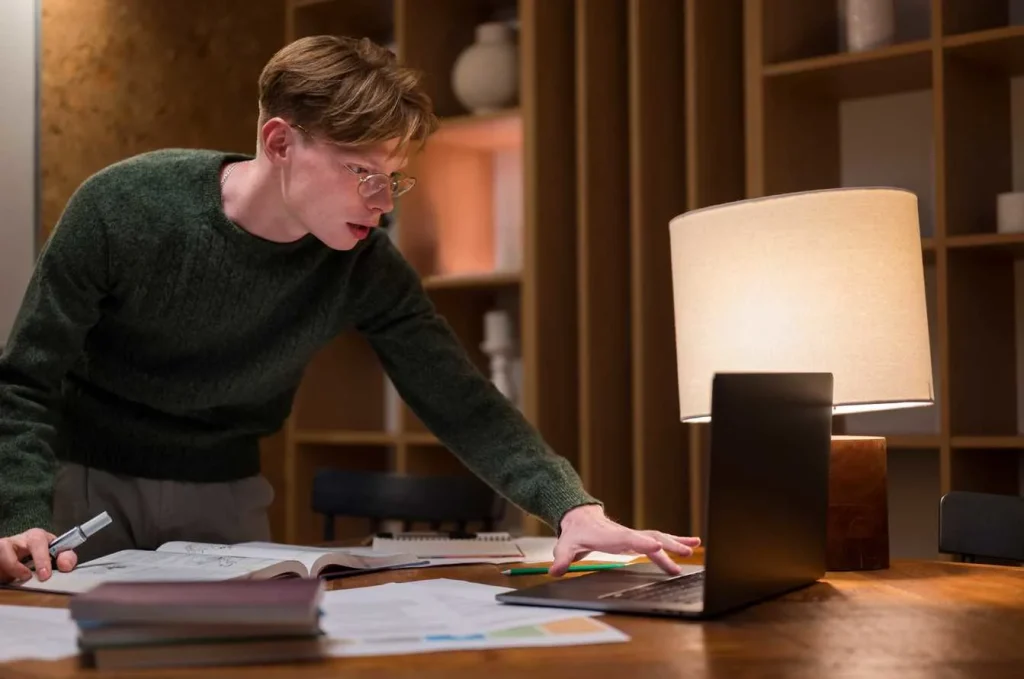 Student studying with books and laptop on desk
