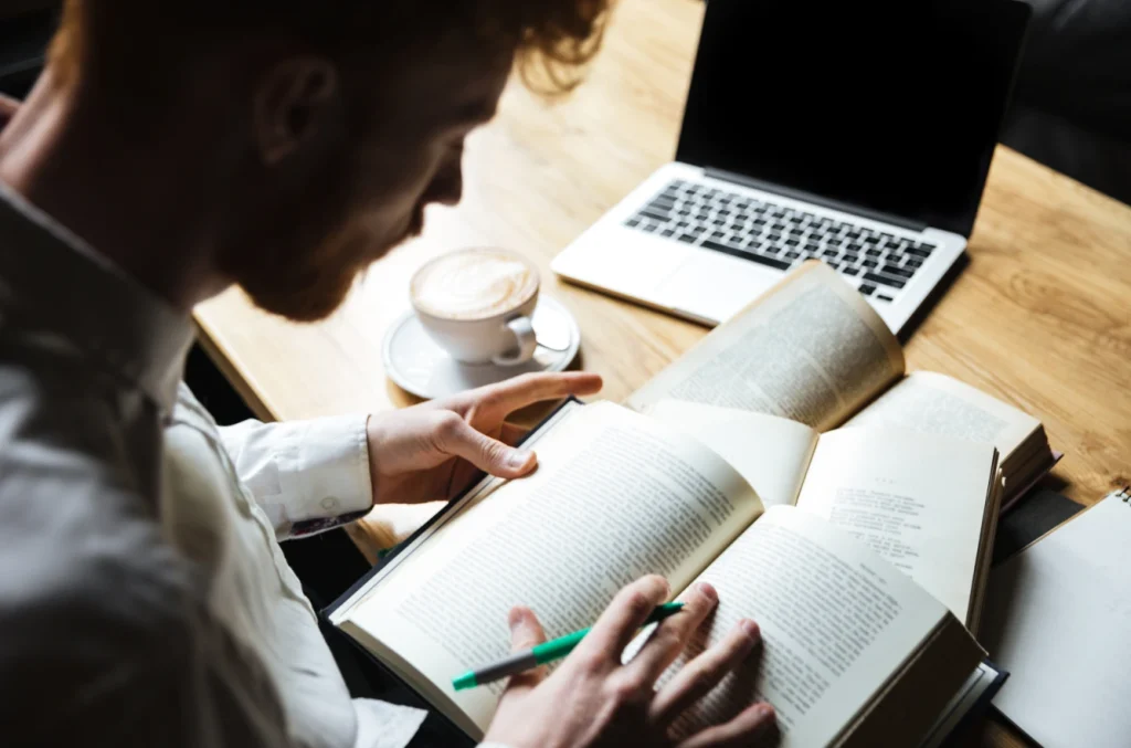 Man reading multiple books at a desk